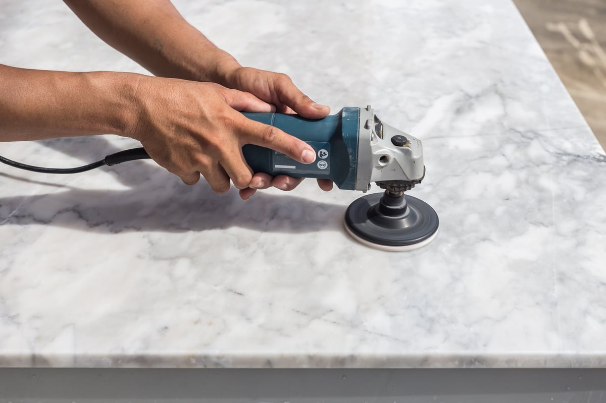 Marble polishing in Long Island — technician diamond-polishing a marble countertop with a wet handheld polisher